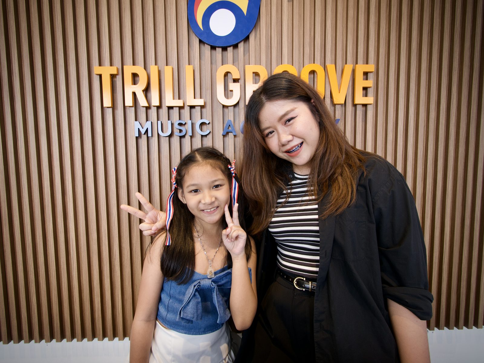 นักเรียนถ่ายภาพหน้าโลโก้ Trill Groove